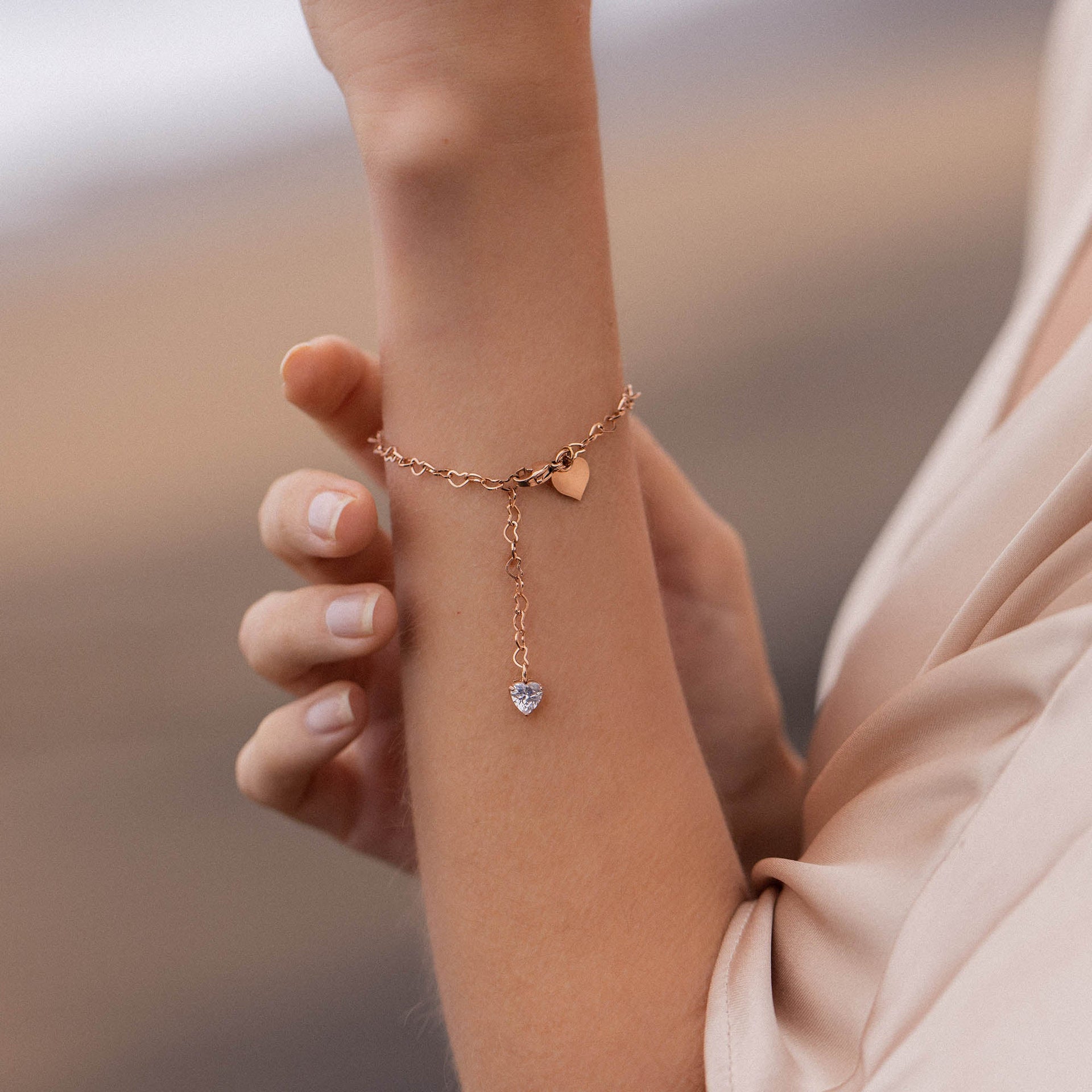 Roségoldenes Armband mit Herzanhängern, getragen am Handgelenk, von PURELEI.