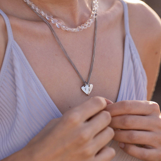 Silberne Herz-Halskette mit Initialen, getragen über einem blauen Top, von PURELEI.