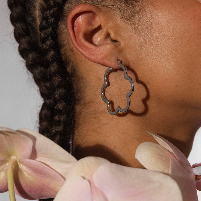 PURELEI Bloom Ohrringe aus nickelfreiem, silbernem Edelstahl in Blumenform, getragen mit zarter Blüte.