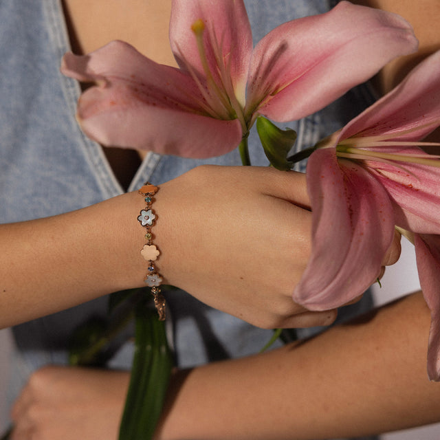 Roségoldenes Armband mit blühenden Anhängern, getragen mit Blumen von PURELEI.