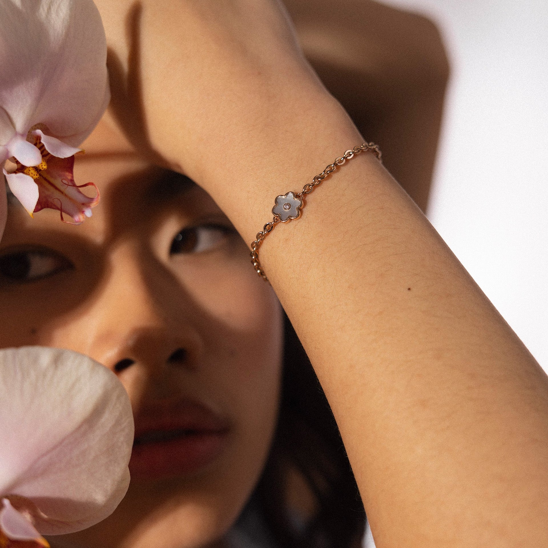 PURELEI Flourish Armband in Roségold mit zartem Blütenanhänger und Perlmutt-Detail am Handgelenk getragen.