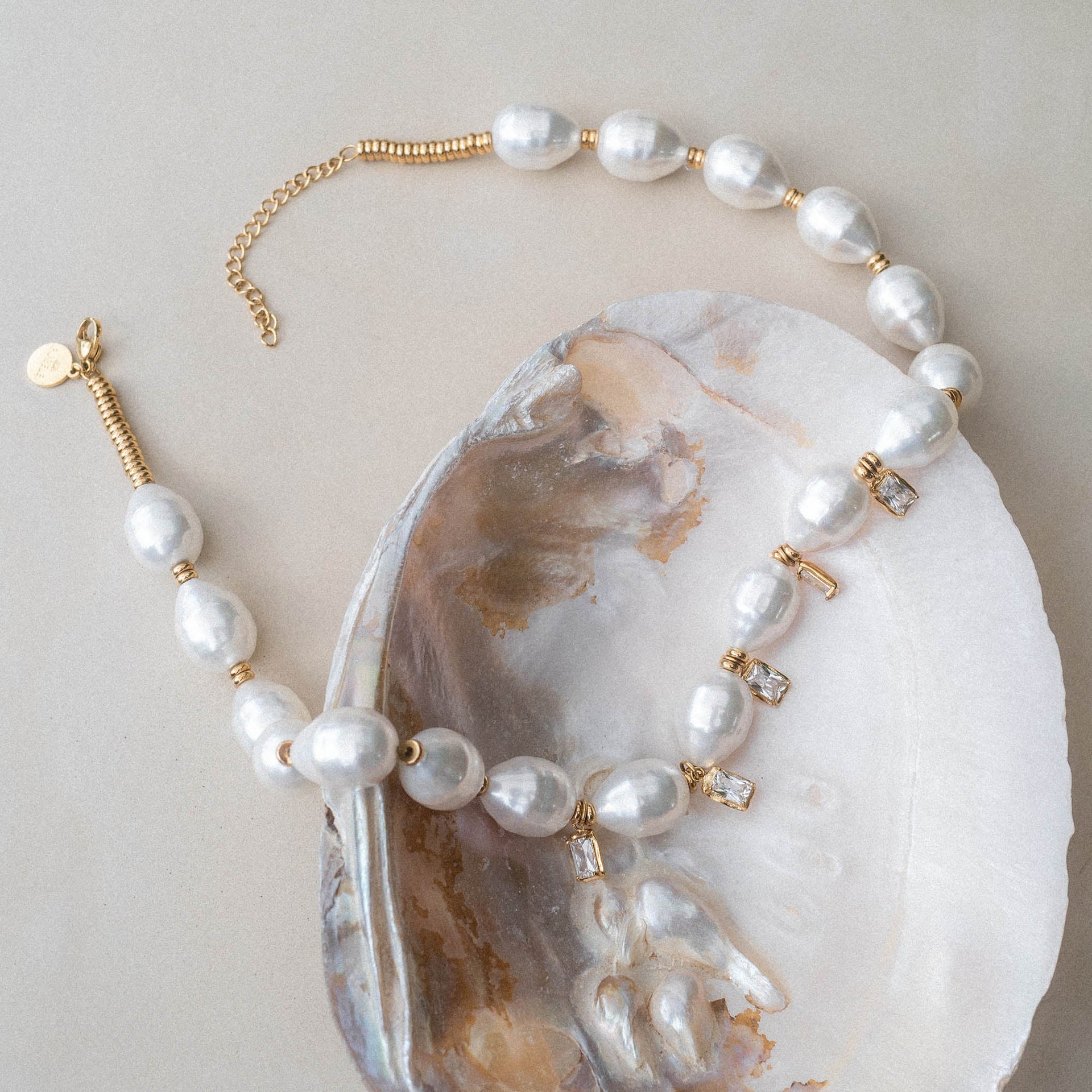 Perlenkette mit goldenen Akzenten, elegant auf Muschel präsentiert – PURELEI.