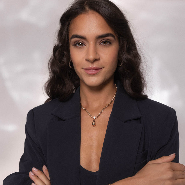 Elegante Silberkette mit Tropfenanhänger, getragen von einer Frau in dunklem Outfit, PURELEI.