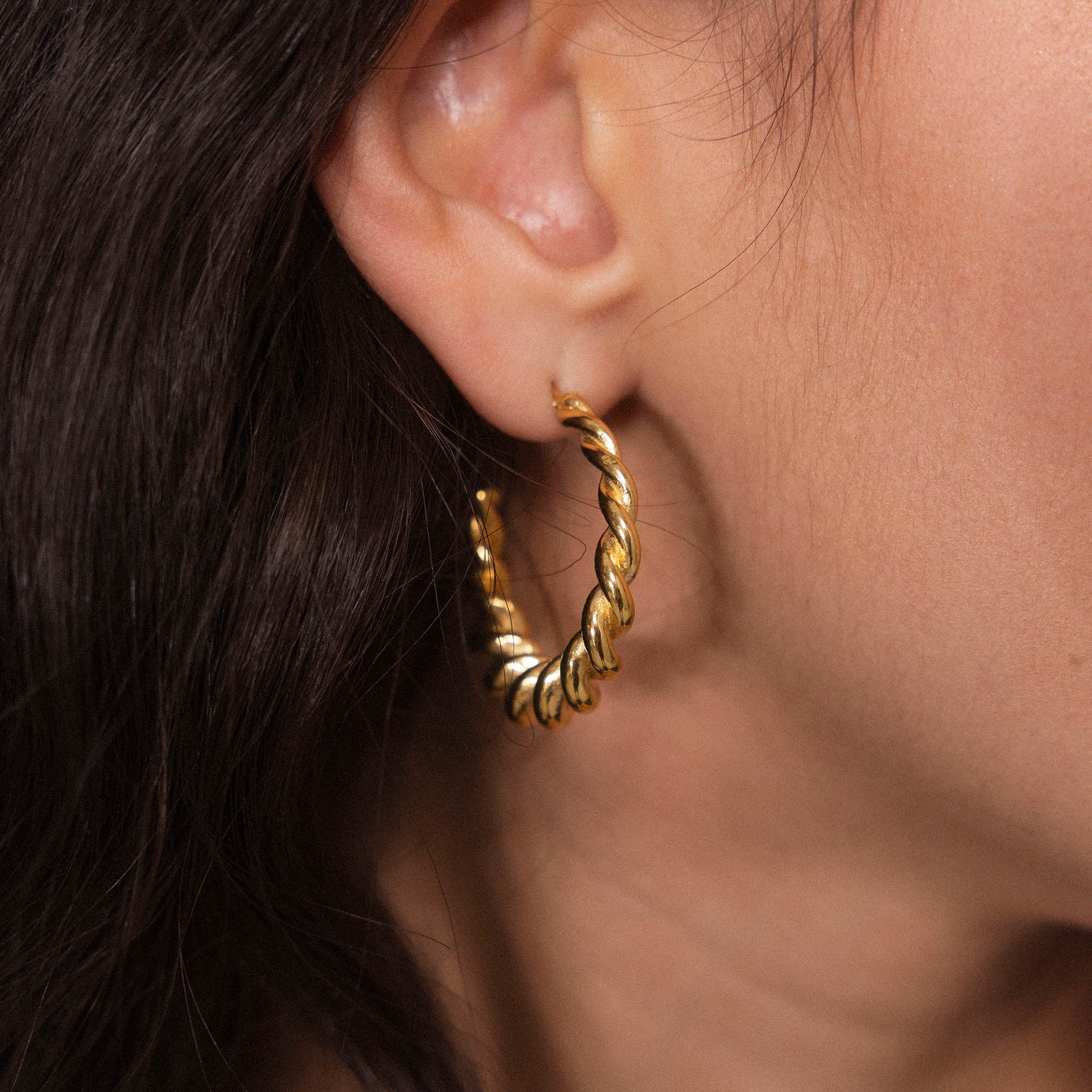 Roségoldene Creolen mit gedrehter Struktur, getragen am Ohr, von PURELEI.