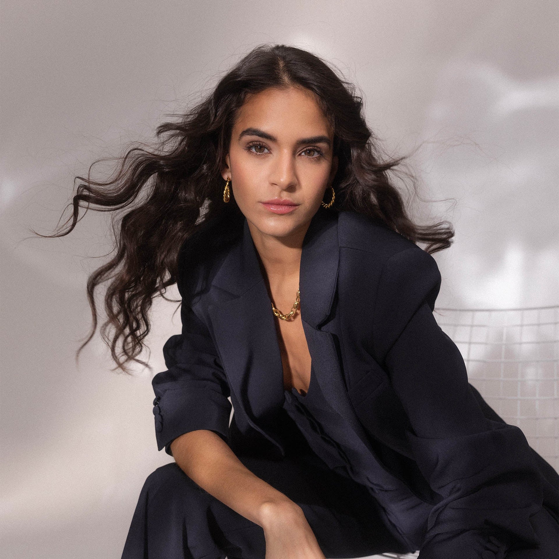 Elegante, goldene Creolen und Kette von PURELEI, getragen in stilvollem, dunklem Outfit.