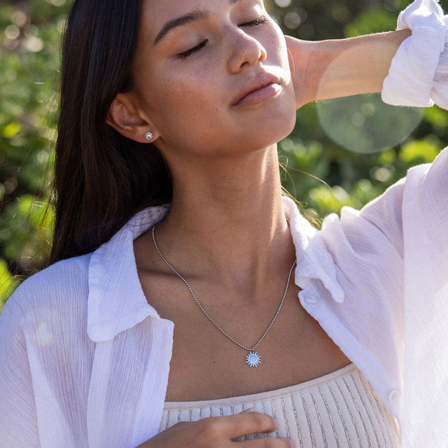 Silberne Kette mit Sonnenmotiv, getragen von einer Frau im Freien, PURELEI inspiriert.