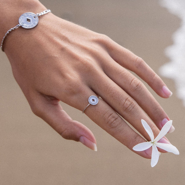 Silbernes Armband und Ring mit filigranem Design, getragen mit einer Blüte, PURELEI.