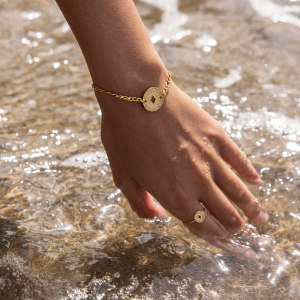 Lolani Armband von PURELEI in Gold mit hawaiianischem Coin, wasserfest, zart am Handgelenk im Meeresspiel.
