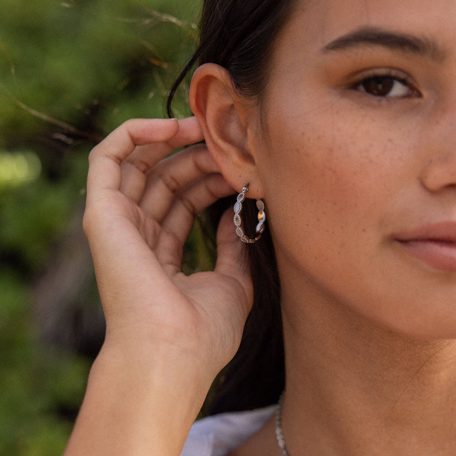 Silberne Creolen mit Muschel-Details, getragen von einer Frau, PURELEI inspiriert.