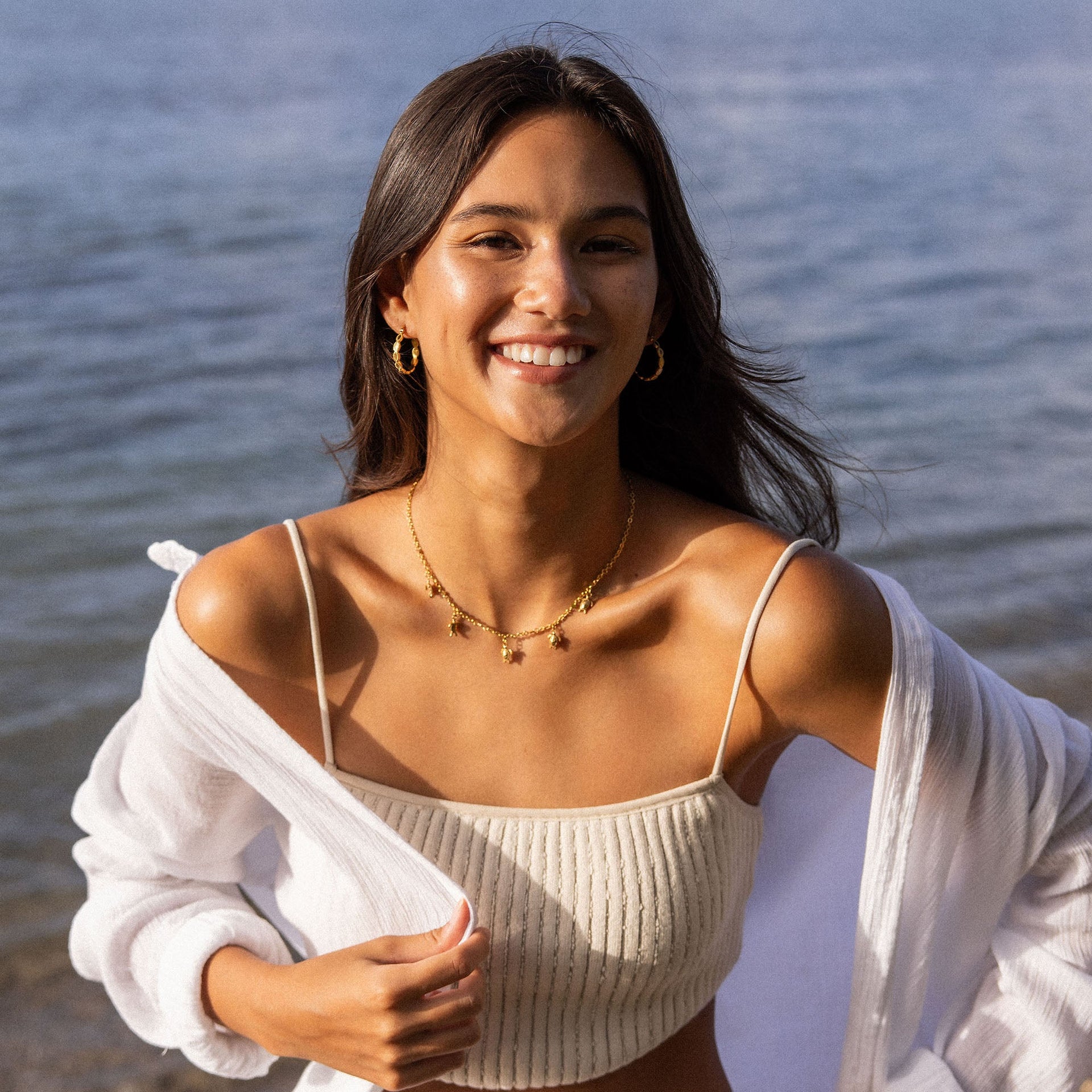 Goldene Kette mit Sternenanhängern, getragen am Strand, PURELEI inspiriert.