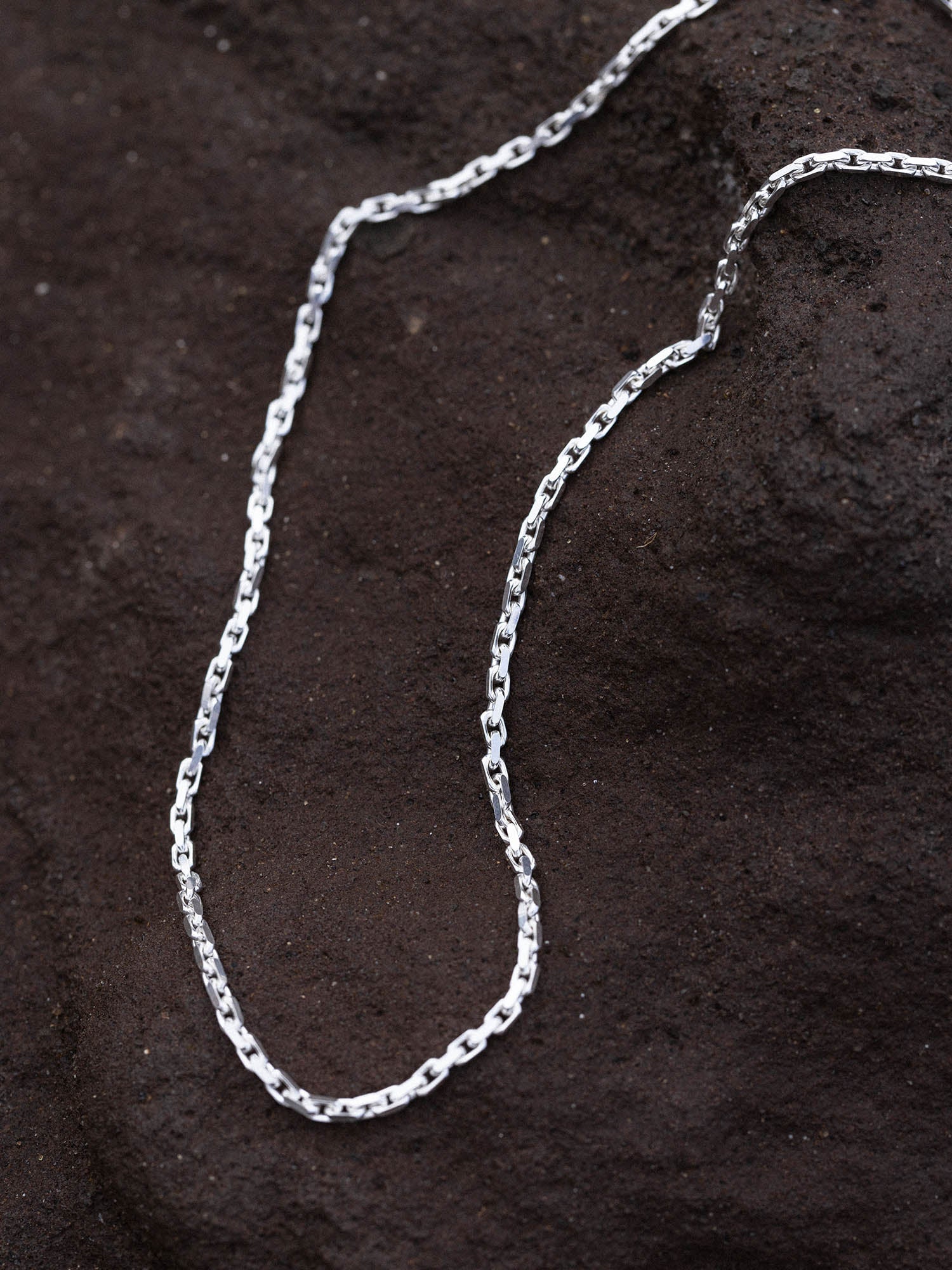 Gleam Kette von PURELEI, edle Silber-Ankerkette mit ineinander verschlungenen Gliedern auf dunklem Lavastein.