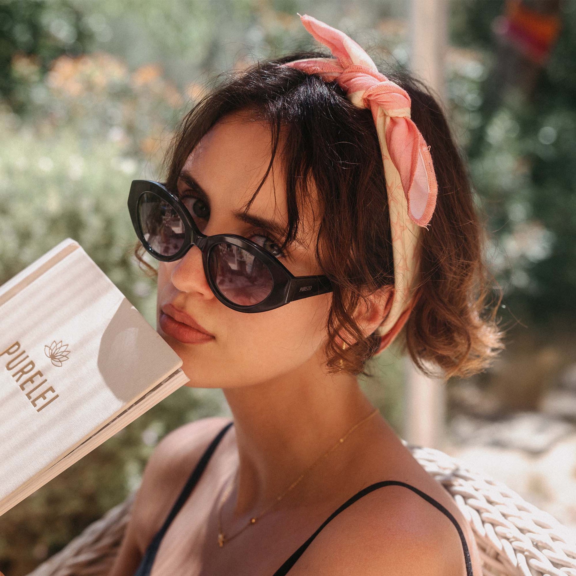 Schwarze Sonnenbrille und zarter Haarschal, PURELEI, in warmem Licht, entspannte Sommerstimmung.