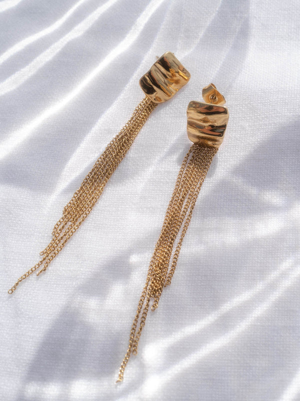 PURELEI Allure Ohrringe aus 14K goldvergoldetem Edelstahl mit filigranen Ketten und elegantem, organischem Design auf weißem Stoff.