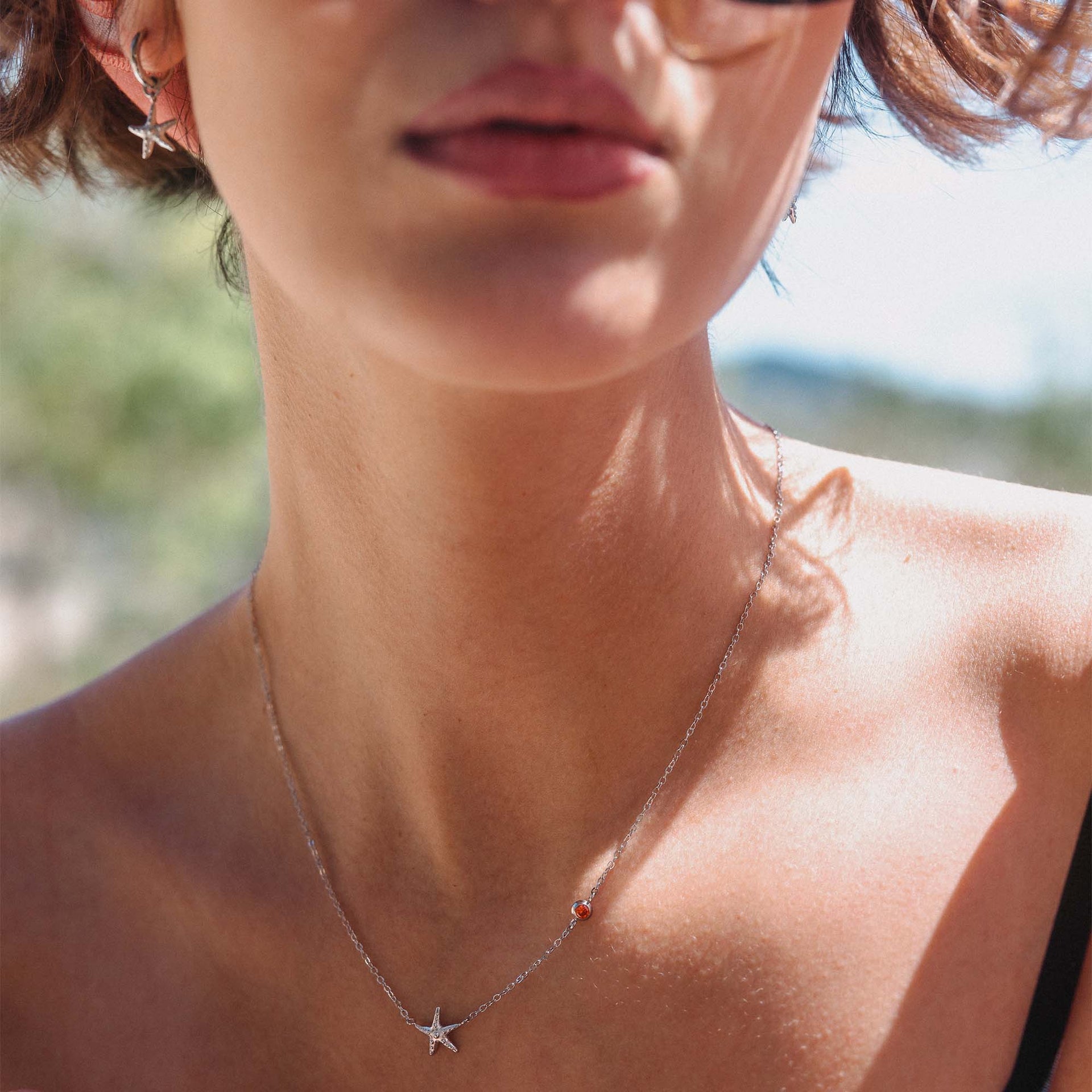 Silberne Kette mit Stern-Anhänger, getragen in sonniger Umgebung – PURELEI.