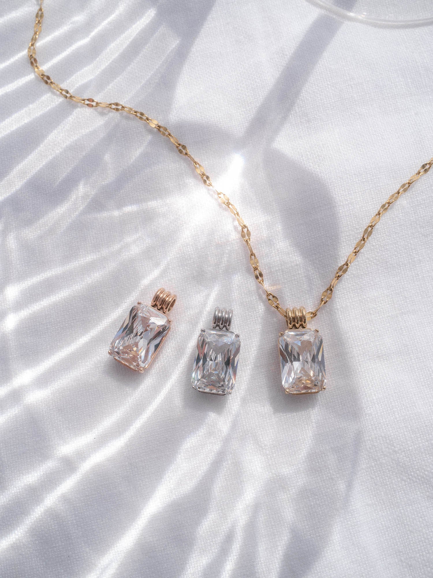 Coastal Chic Charm Anhänger in Gold, Silber und Roségold mit facettiertem Zirkonia auf weißem Stoff, PURELEI.