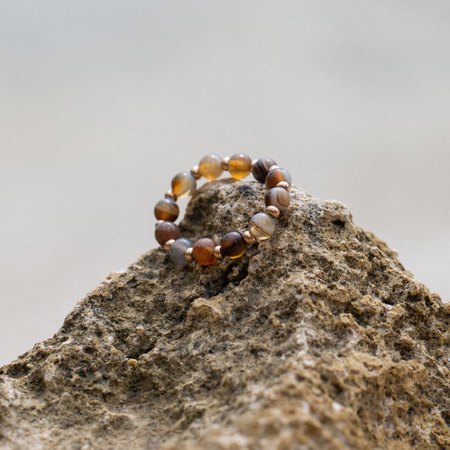 Anxiety Mahina Club Mokupuni Ring mit Natursteinperlen in warmen Erdtönen auf rauem Lavagestein, PURELEI.