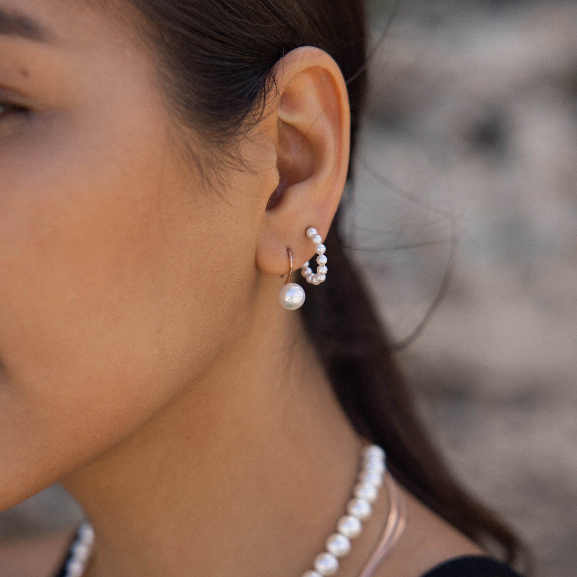 Wasserfeste Creolen mit weißen Perlen von PURELEI, elegant und feminin am Ohr getragen.