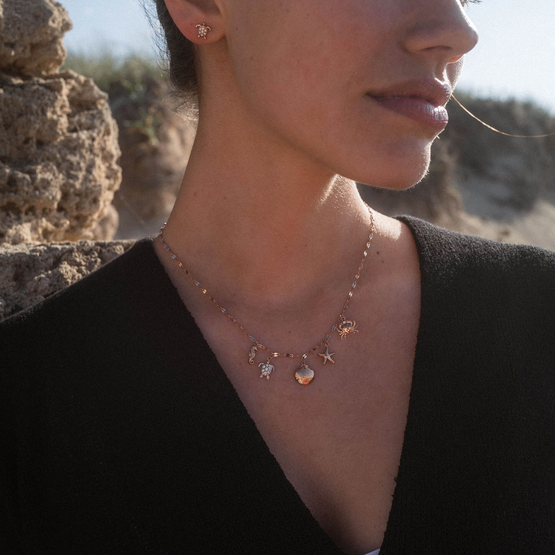 Goldene Kette mit maritimen Anhängern, getragen von PURELEI, in warmem Licht.