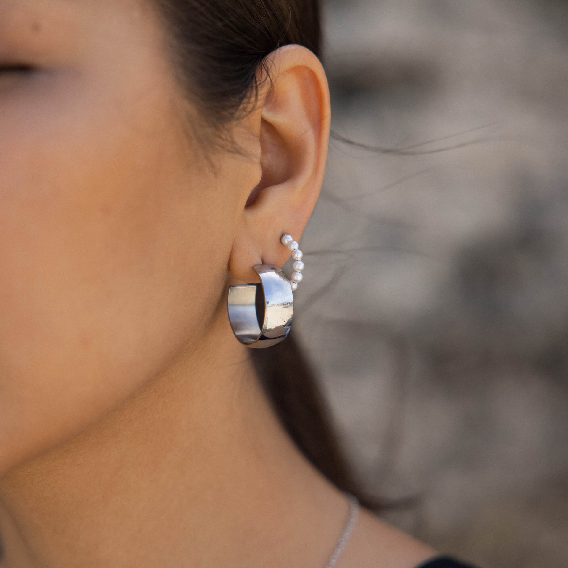 Silberne Creolen mit glänzender Oberfläche, getragen mit zarten Perlen, PURELEI-Stil.