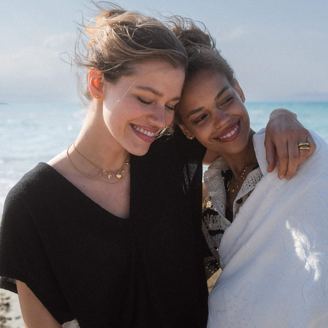 Zwei Frauen am Strand, eine trägt eine zarte PURELEI Kette mit Sternen, sonnige Stimmung.