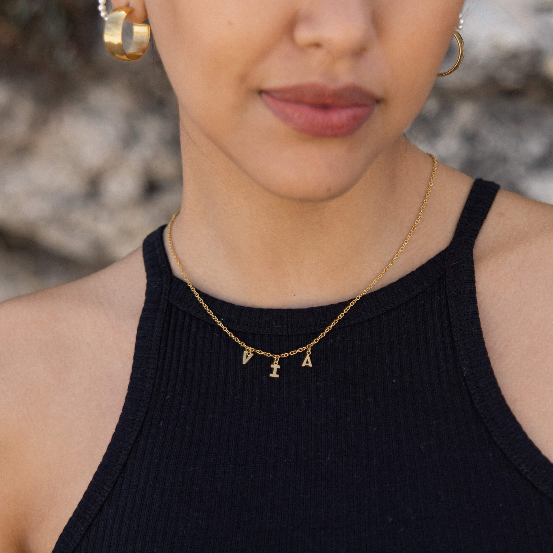 Roségoldene Kette mit Buchstabenanhängern, getragen mit schwarzem Oberteil – PURELEI.