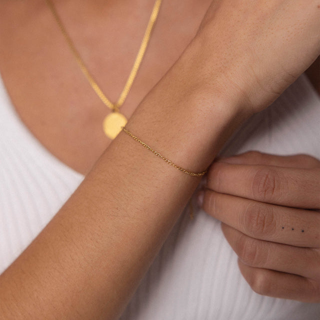 PURELEI Kaula Armband aus 18K Gold, feines gedrehtes Design, elegant am Handgelenk getragen, warm und feminin.
