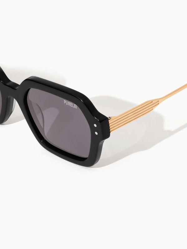 Coastal Core Sonnenbrille von PURELEI mit schwarzem Acetatgestell und goldfarbenem Metallbügel, elegant und modern.