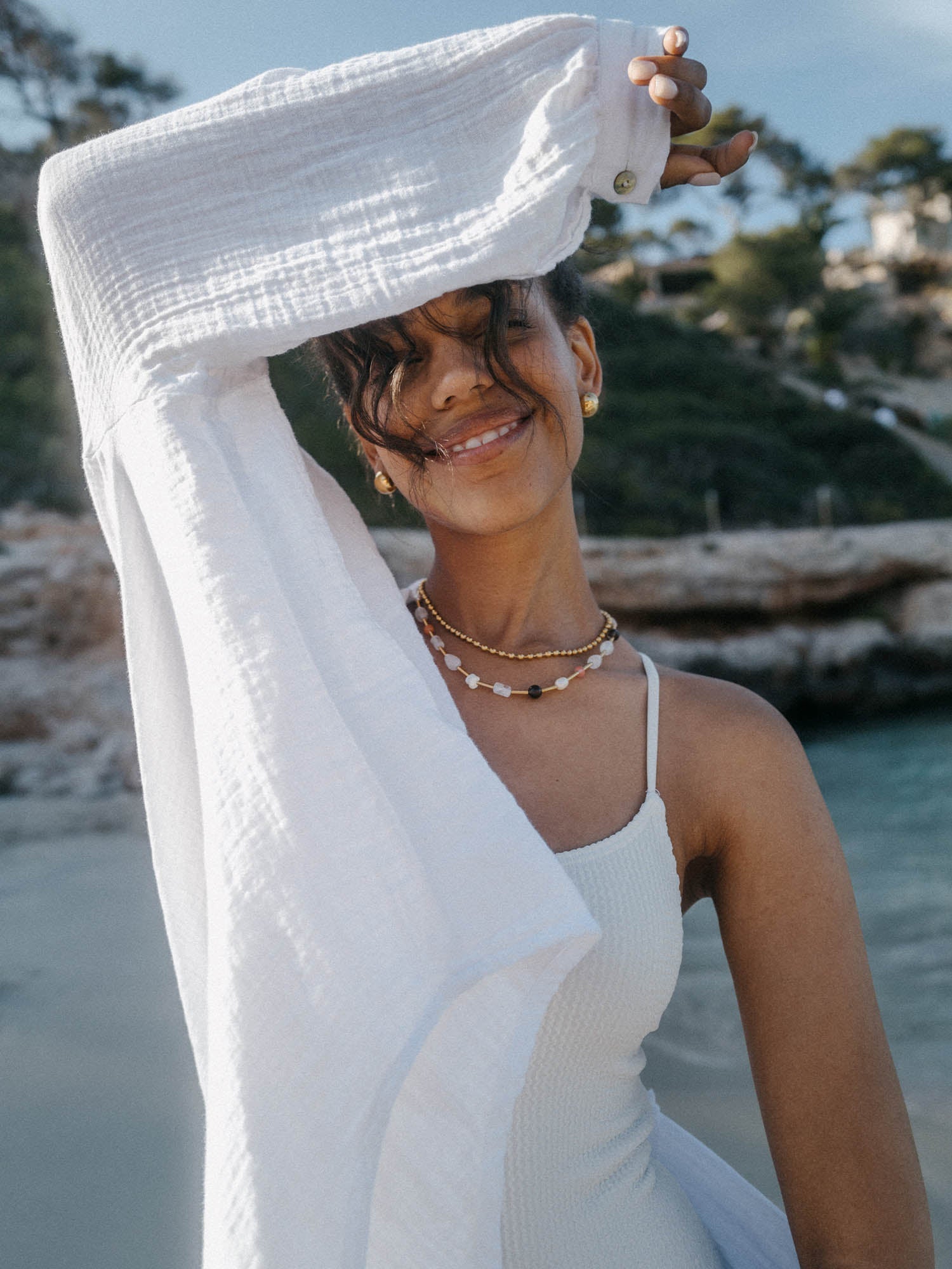 Weißes, luftiges Kleid mit PURELEI Schmuck, strahlende Stimmung am Strand.