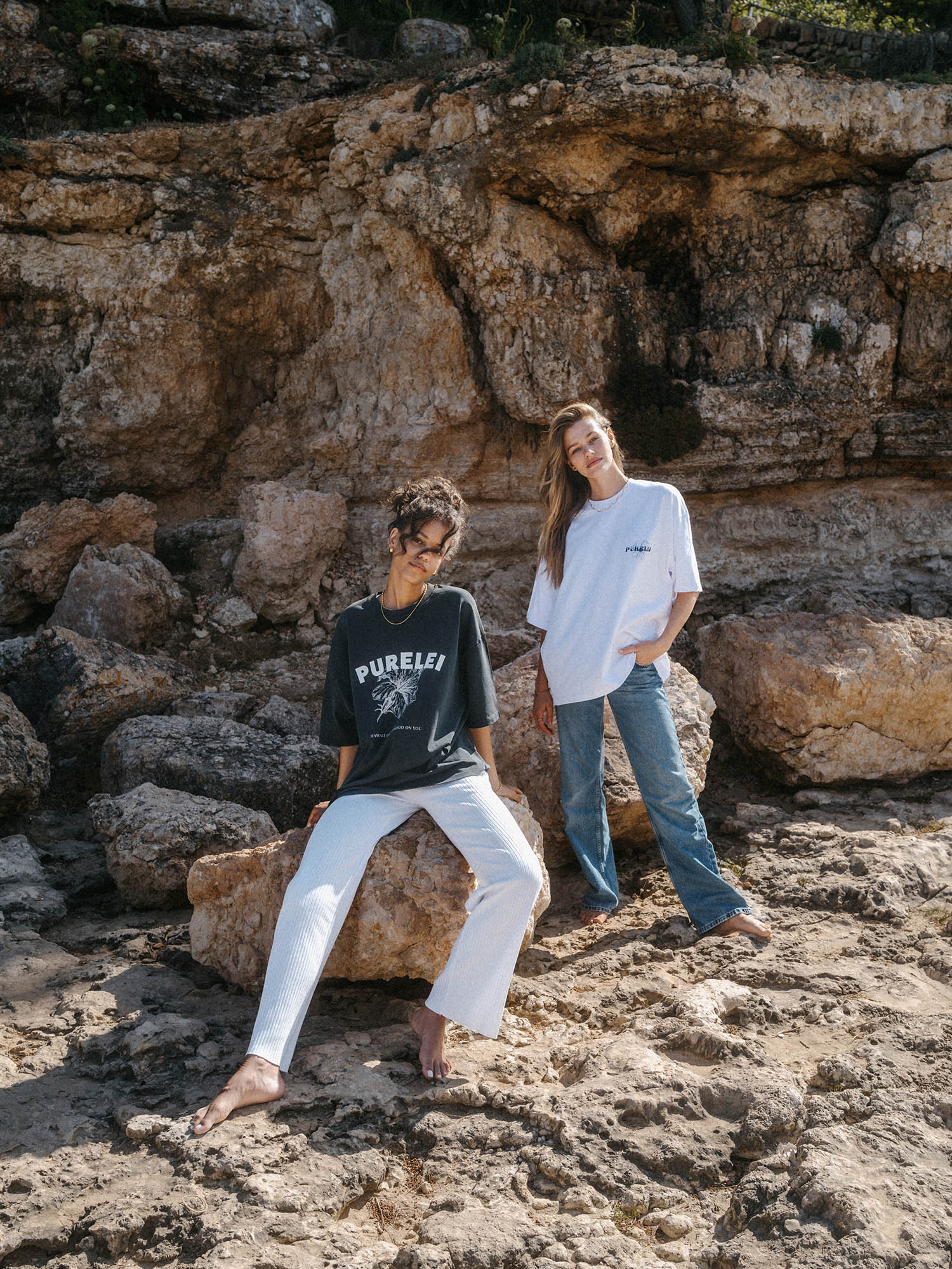 Zweifarbiges PURELEI Ocean T-Shirt aus Baumwolle mit Hawaii-inspiriertem Print, lässig am Felsen getragen.