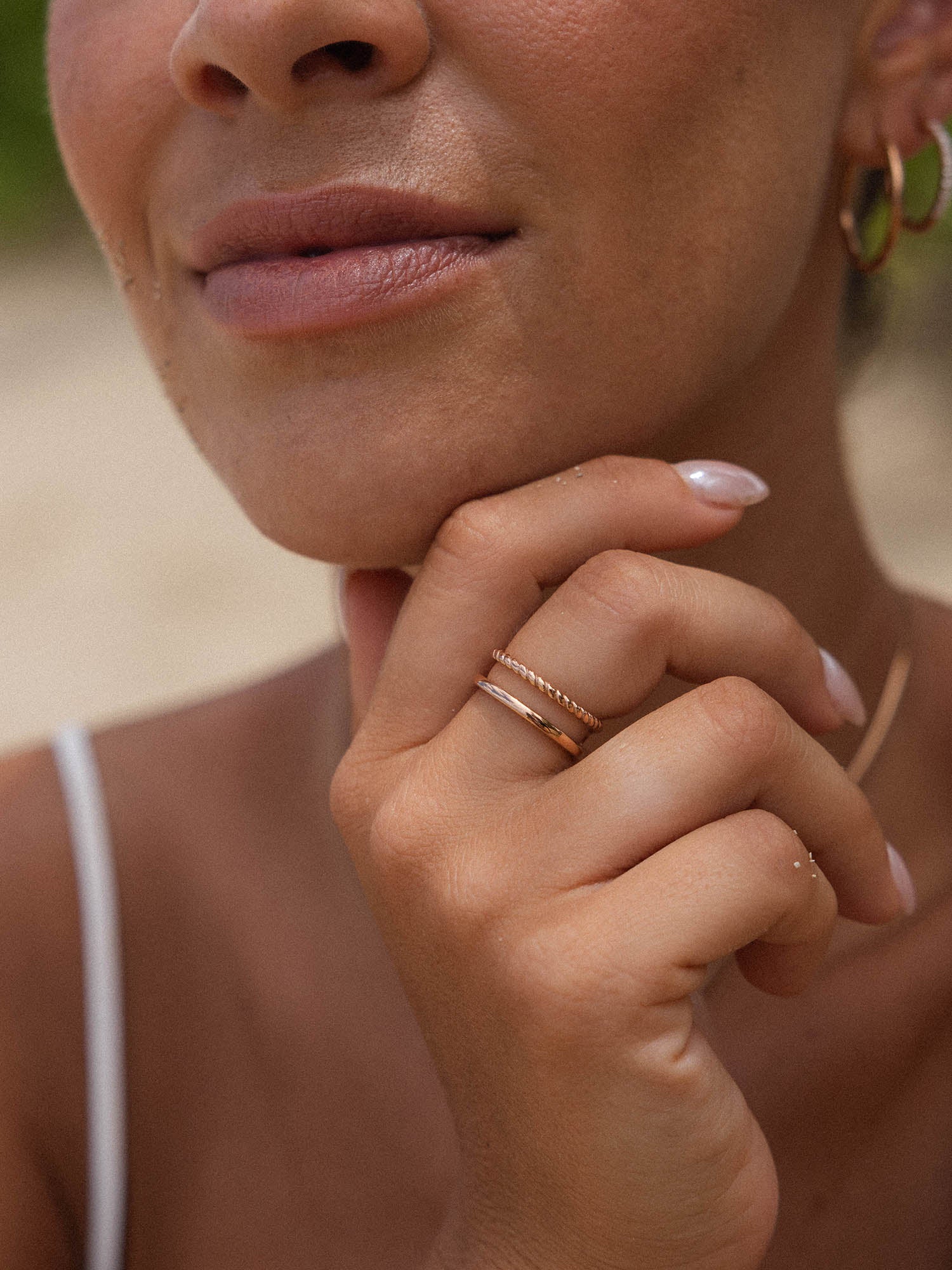 Zarte, roségoldene Ringe von PURELEI an einer Hand, umgeben von warmem Licht.