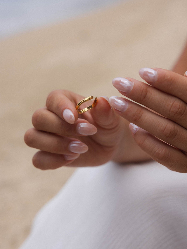 Roségoldener Ring in zarten Händen, umgeben von sandiger Atmosphäre – PURELEI.