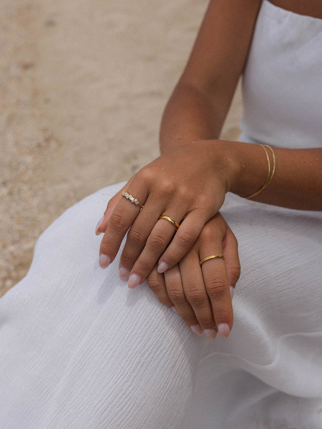 Zarte Ringe aus Roségold und Silber, getragen auf einer weißen Decke, PURELEI Stil.