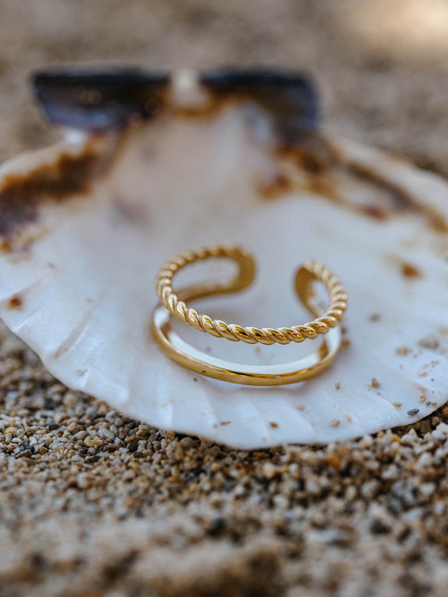 Zwei goldene Ringe auf einer Muschel, PURELEI, elegant und natürlich.