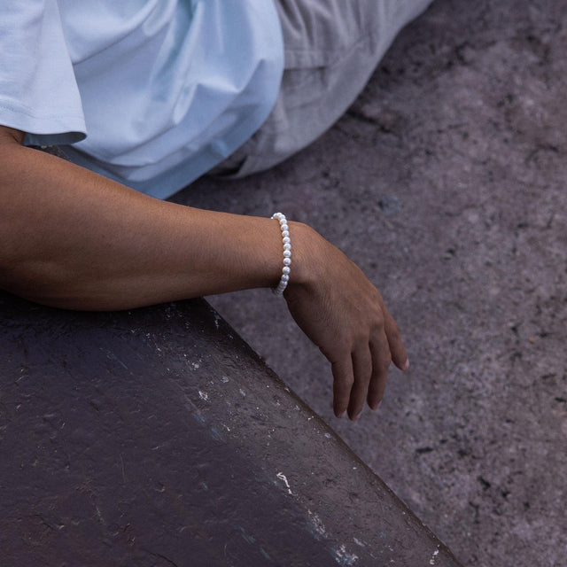 Weißes Armband aus Perlen, getragen am Handgelenk, inspiriert von PURELEI.