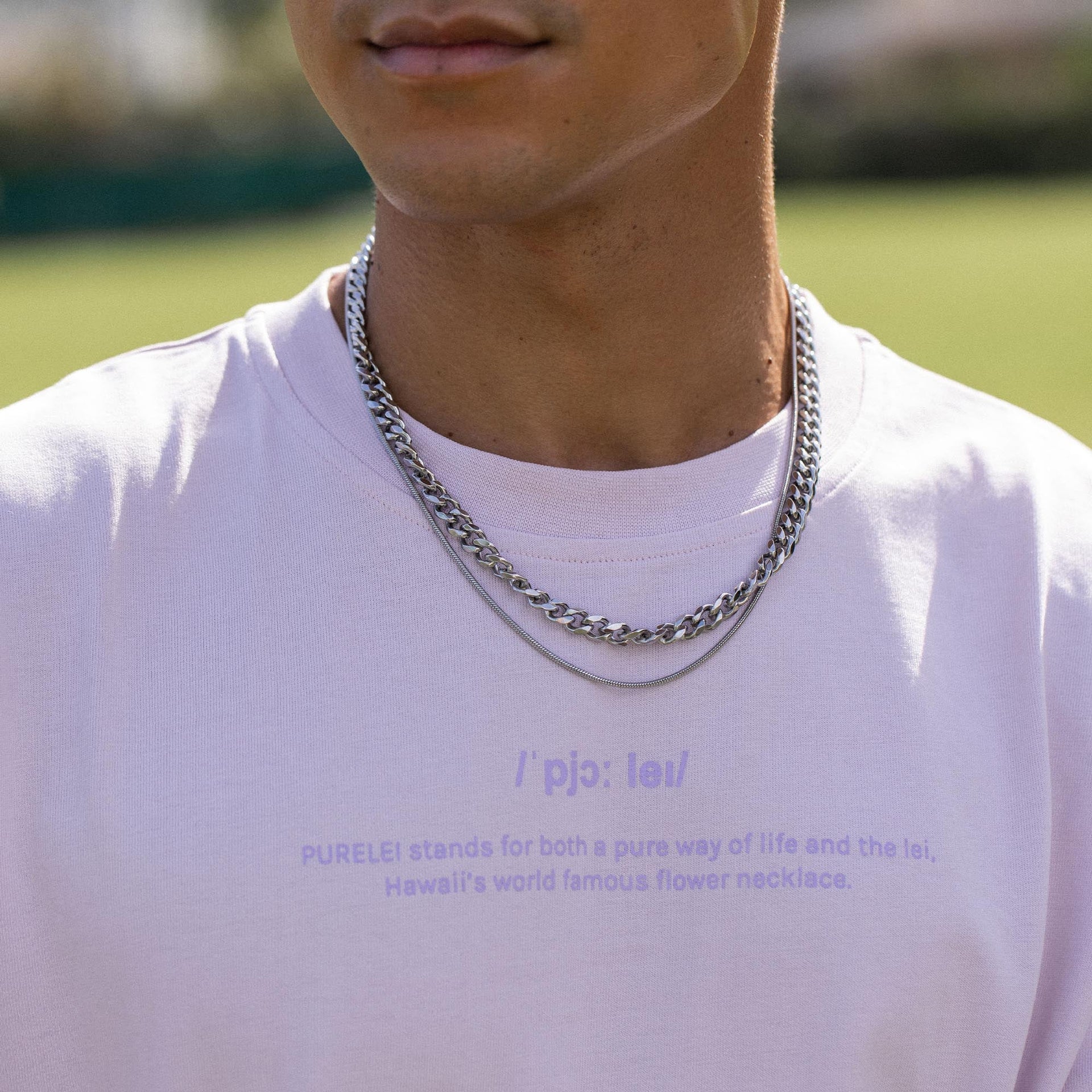 Silberne Kette von PURELEI, elegant und modern, getragen auf einem weißen T-Shirt im Freien.