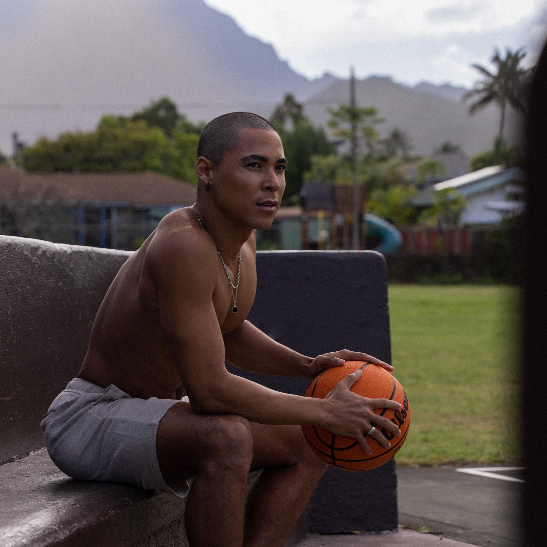 Mann mit Basketball, goldene Kette von PURELEI, entspannte Stimmung im Freien.