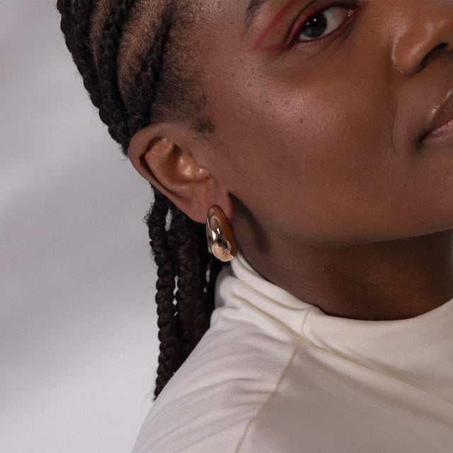 PURELEI Big Drop Ohrringe in glänzendem Gold, tropfenförmig, elegant und zeitlos, getragen am Ohr.