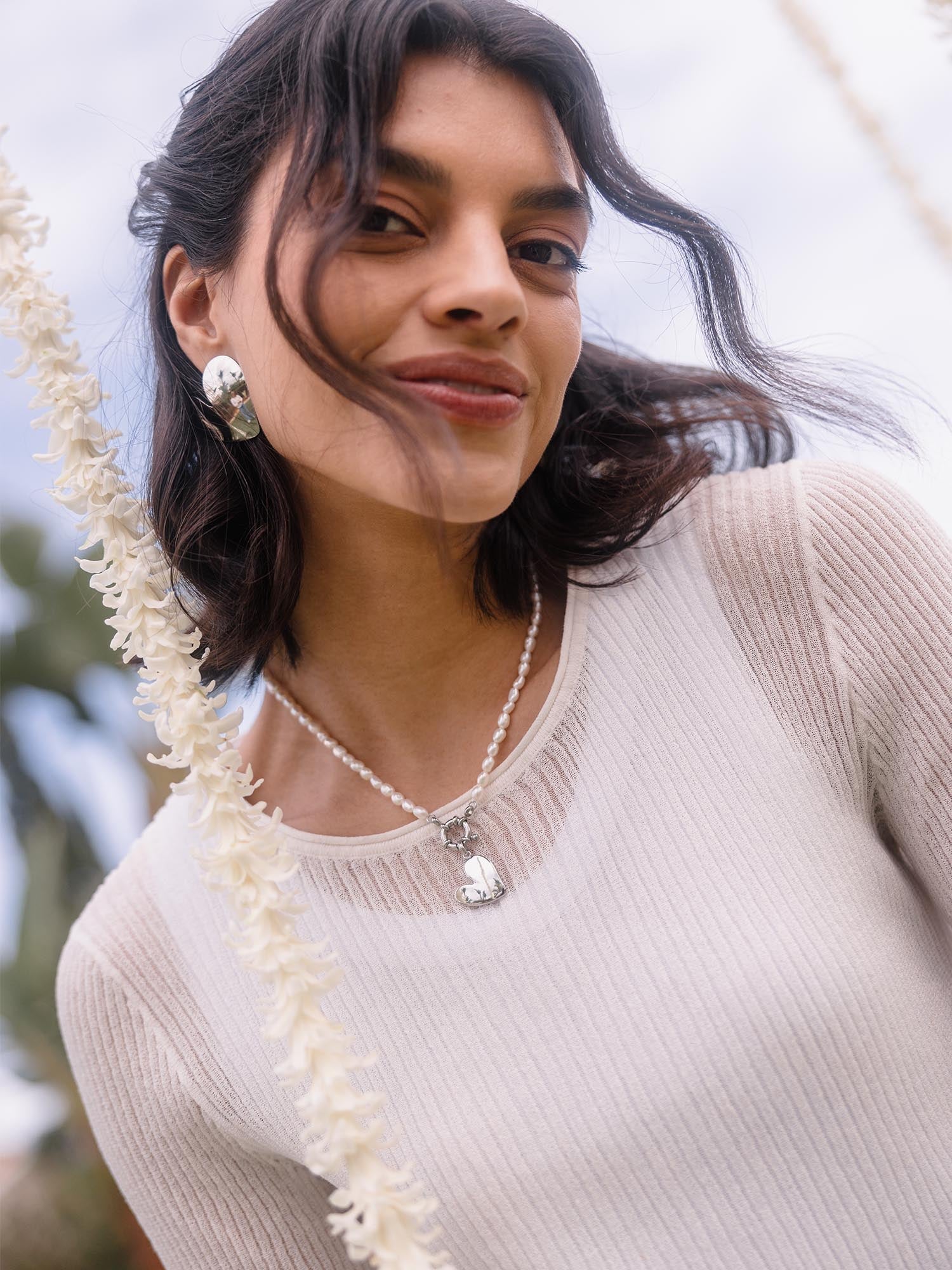Silberne Ohrringe und Kette mit Herz-Anhänger, getragen von einer Frau, PURELEI inspiriert.