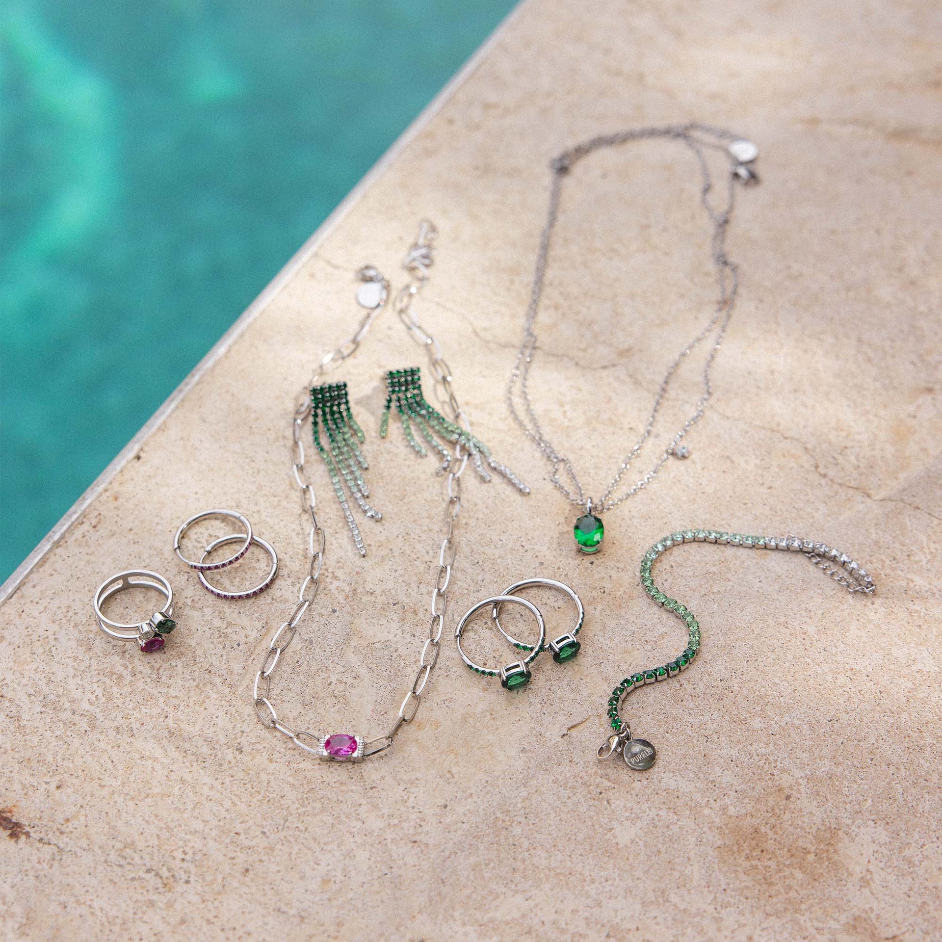 Silberne Schmuckstücke von PURELEI auf hellem Untergrund, umgeben von Wasser, elegant und frisch.