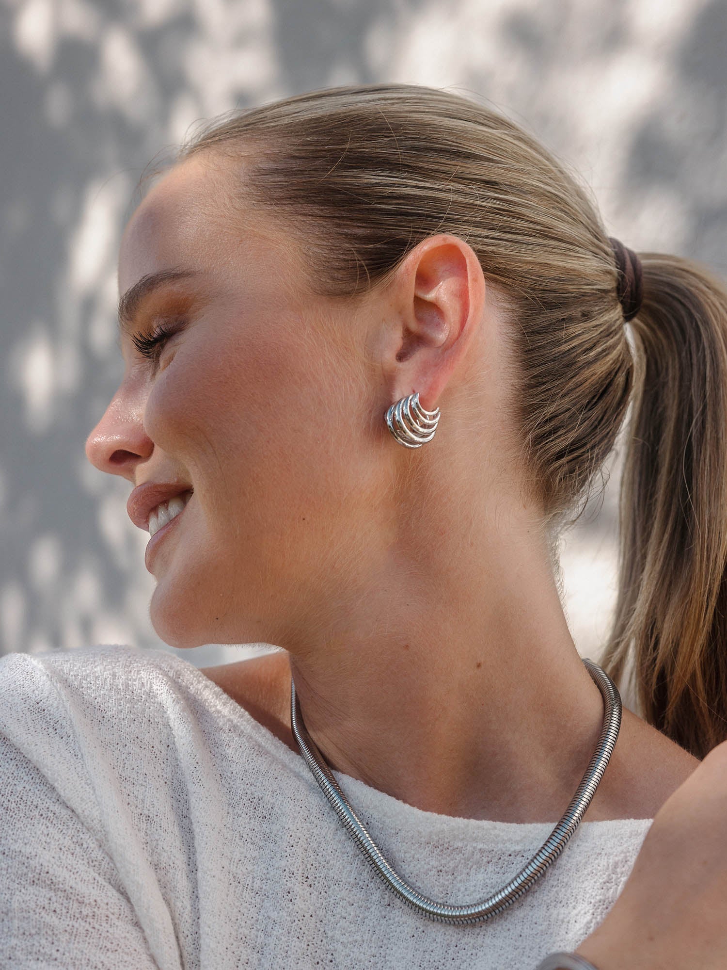 Silberne Creolen und Kette von PURELEI, elegant und modern, strahlen zeitlose Schönheit aus.