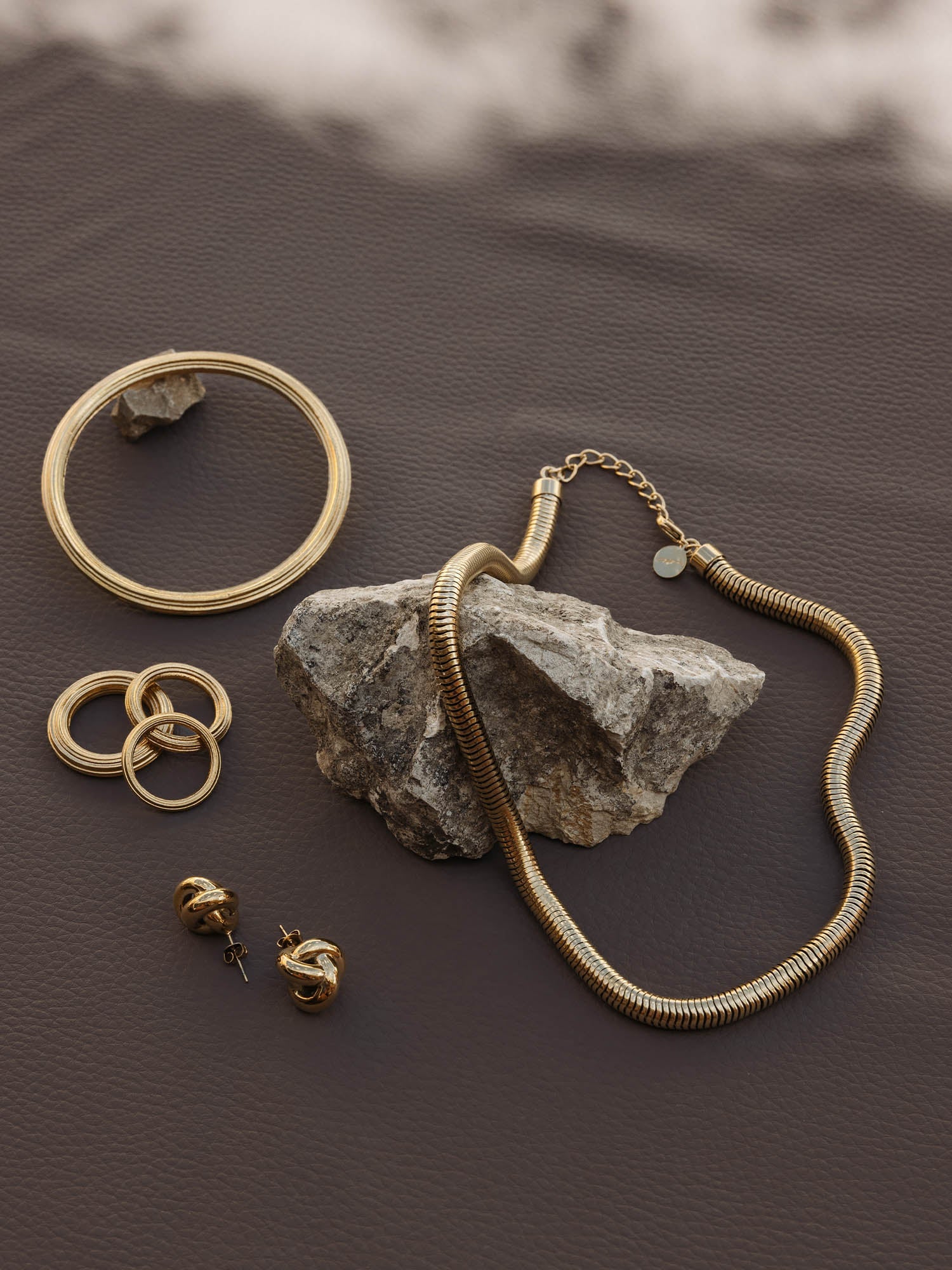 Silberne Schmuckstücke von PURELEI auf braunem Hintergrund, elegant und modern.