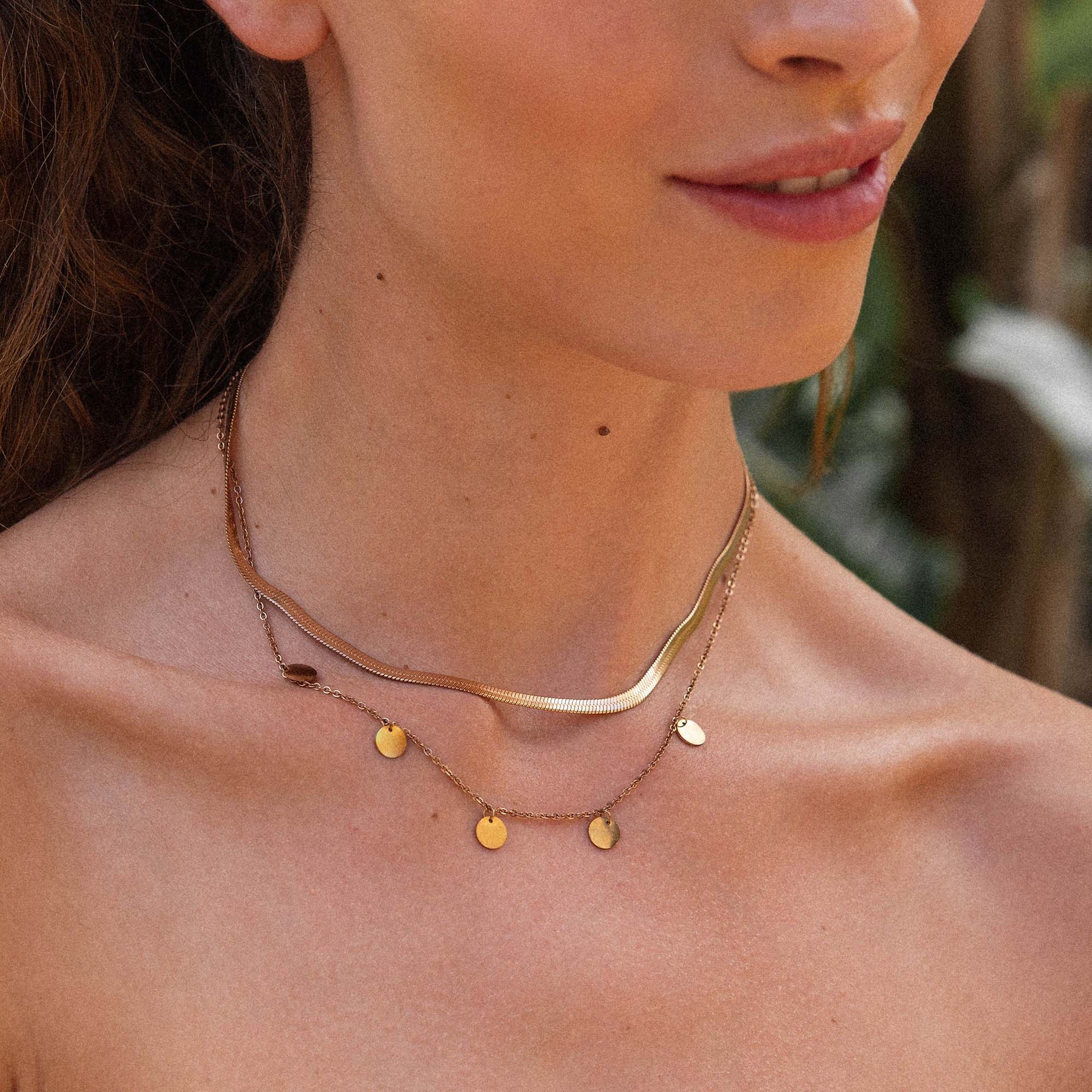 Zarte, roségoldene Kette mit Anhängern, getragen von PURELEI, in tropischer Stimmung.