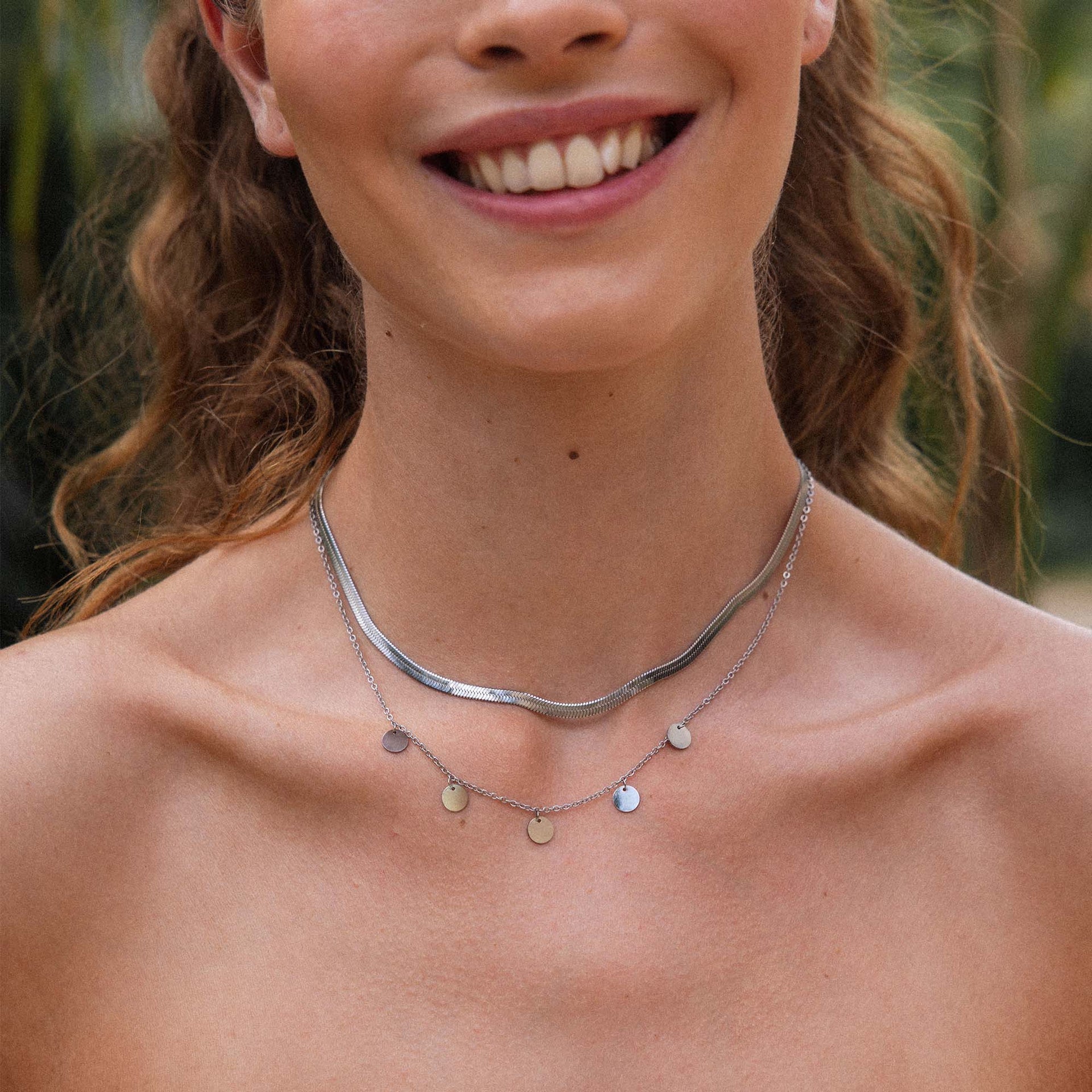 Silberne Ketten von PURELEI, elegant geschichtet mit glänzenden Anhängern, strahlen feminine Leichtigkeit aus.