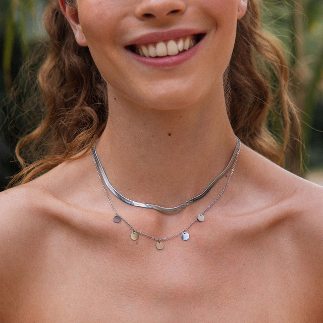 Silberne Ketten von PURELEI, elegant geschichtet mit glänzenden Anhängern, strahlen feminine Leichtigkeit aus.