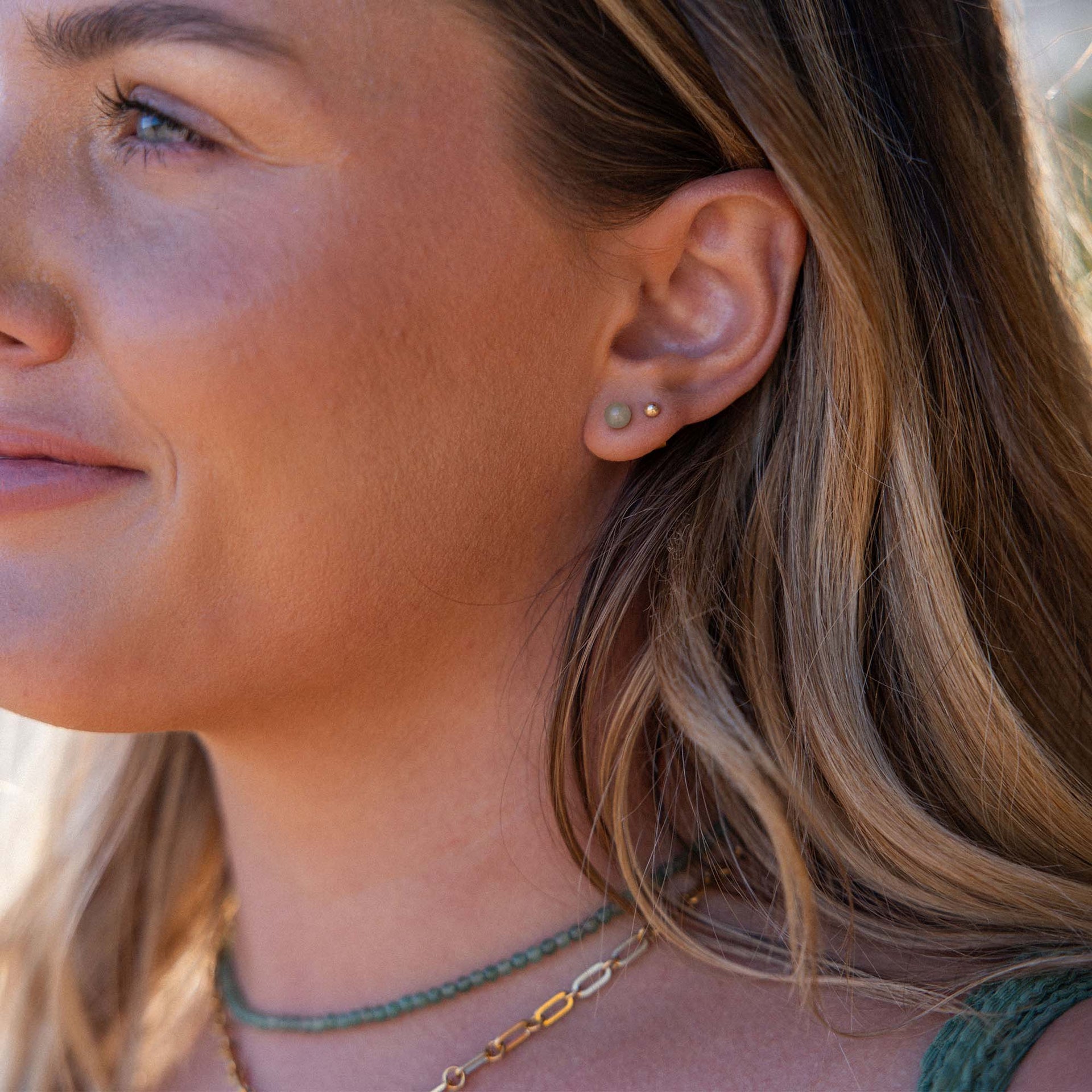 PURELEI Aventurine Ohrringe mit goldenen Ohrsteckern und grünem Stein, getragen im warmen Sonnenlicht am Ohr.