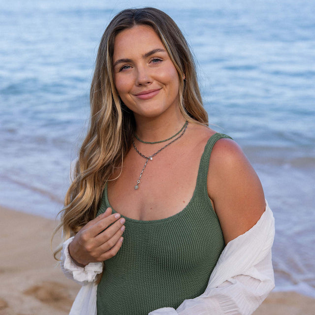 PURELEI Aventurine Charm in Gold mit grünem Aventurin, getragen am Strand, strahlt natürliche Eleganz und Ruhe aus.