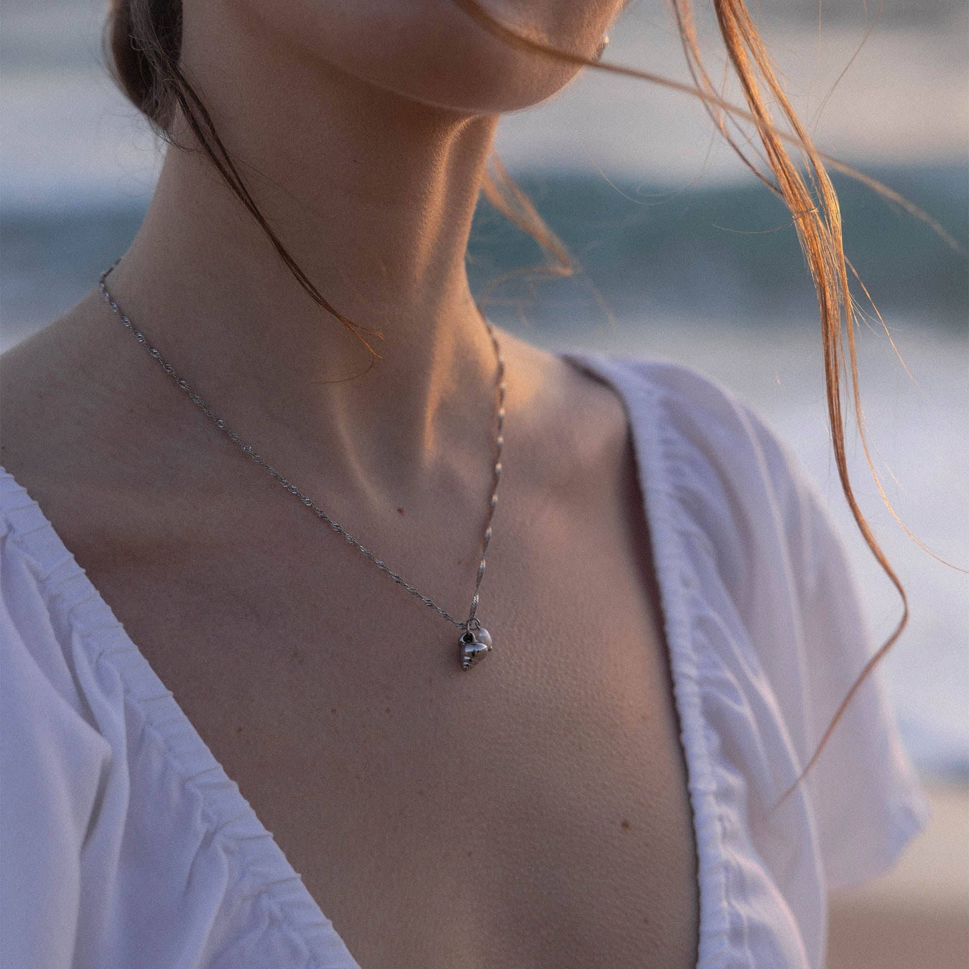 Silberne Kette mit Muschel-Anhänger, getragen am Strand von PURELEI.