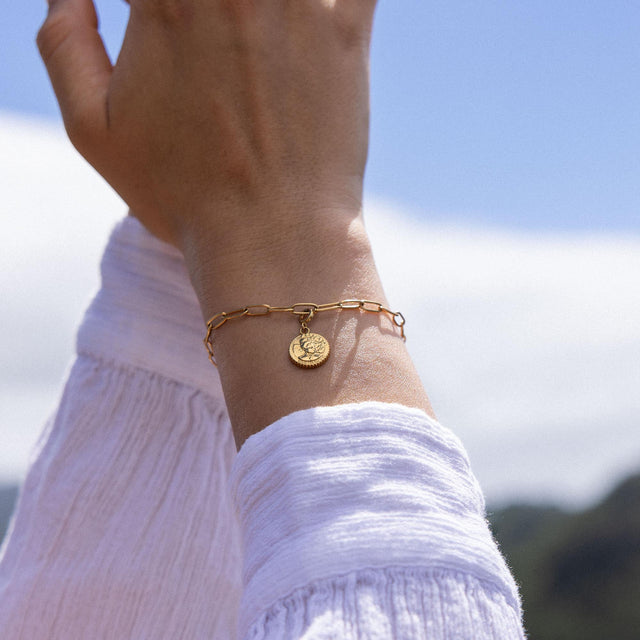 Goldenes Armband mit Anhänger, getragen im Sonnenlicht, von PURELEI.