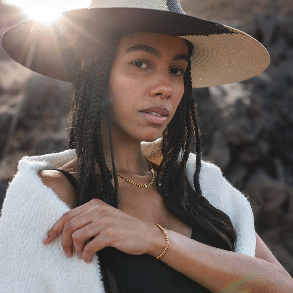 Elegante PURELEI Kette und Armband, silberfarben, getragen mit einem Hut in warmem Licht.