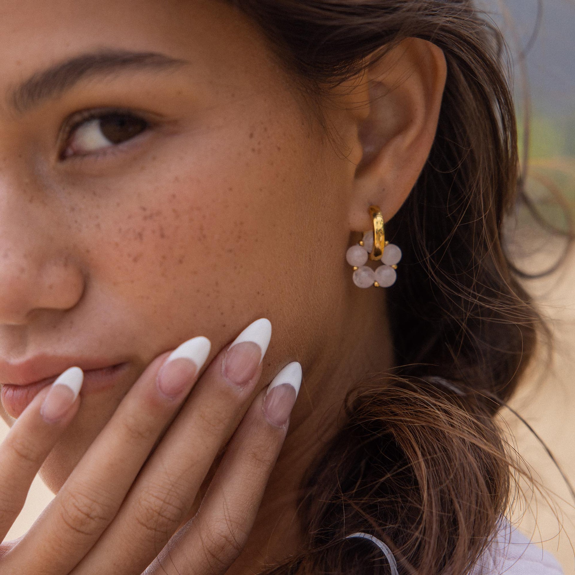Roségoldene Ohrringe mit opalartigen Steinen, getragen von einer Frau mit natürlichem Look – PURELEI.